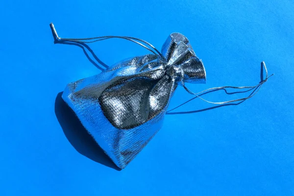 Silver present bag isolated on blue background. Silver shiny gift. Top view