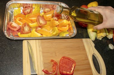 Taze sebzelerle zeytinyağını karıştırmak, pişirilmeye hazır. Vejetaryen sağlıklı organik gıda. Kadın, doğranmış sebzelerin üzerine zeytinyağı döküyor. Yemek pişirme süreci.