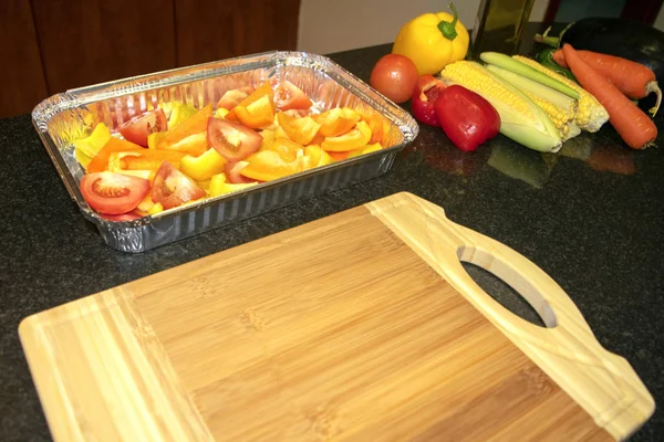 Fresh vegetables mix in aluminum container, prepared to be baked. Vegetarian healthy organic food. Cooking process.