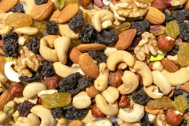 Karışık fındık ve kuru üzümden yapılmış bir arka plan. Sağlıklı atıştırmalık ve yiyecek. Kaju, badem, kuru üzüm, ceviz, fıstık. Üst Manzara. Çeşit çeşit fındık ve kuru üzüm..