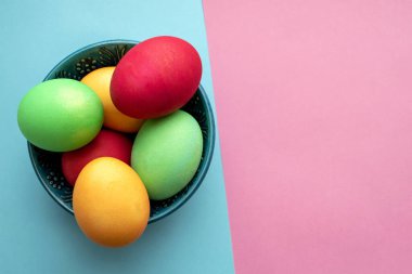 Mavi bir kasede boyanmış Paskalya yumurtaları. Fotokopi alanı ile karışık pembe ve mavi arka plan. Gerçek Hıristiyan ziyafetinin sembolü. Paskalya dekorasyon arkaplanı