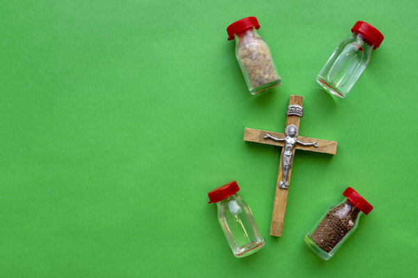 Jerusalem Frankincense, Holy water, Holy oil, Holy Earth and Olive Wood Crucifix on green background with copy space. Christian Gifts, religious symbols.
