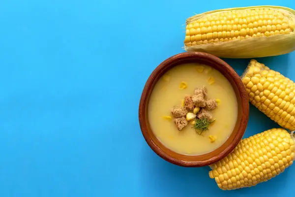 玉米奶油汤在一个褐色碗与新鲜的甜玉米蓝色背景与复制空间 顶部视图 — 图库照片