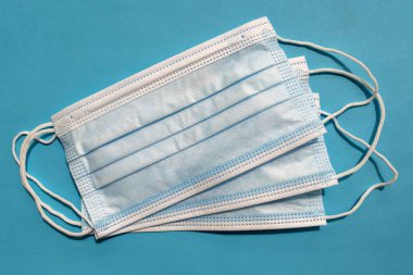 Mavi arka planda cerrahi tek kullanımlık yüz maskeleri. Üst Manzara. Tıbbi mavi maskeler. Virüslere karşı önleyici önlem olarak tıbbi solunum bandajları. PPE ekipmanı 