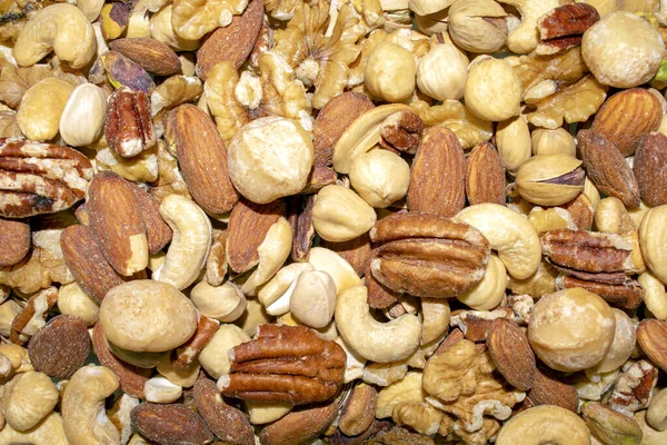 Background made of mixed nuts. Healthy snack and food. Salted and spicy pistachios, cashew, pecan, walnuts, macadamia and almond. Top view. Assorted nuts. Fresh nuts.