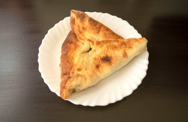 Ünlü geleneksel Arapça, Orta Doğu, İsrail mutfağı. Koyu ahşap arka planda ıspanak mankeni. Beyaz tabakta ıspanaklı üçgen pasta