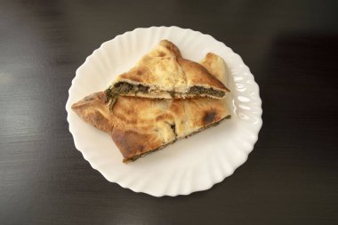 Ünlü geleneksel Arapça, Orta Doğu, İsrail mutfağı. Koyu ahşap arka planda ıspanak mankeni. Beyaz tabakta ıspanaklı üçgen pasta