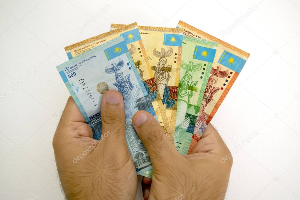 Kazakhstan national currency. KZ money banknotes. Man holds tenge in his hands isolated on light white background.
