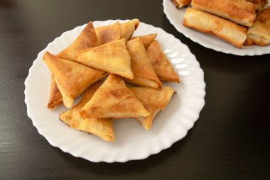 Ünlü geleneksel Arapça, Orta Doğu, Asya mutfağı. Üçgen Arap tavuklu samosa ve koyu ahşap arka planda börek. Beyaz tabakta bir sürü mini samosa