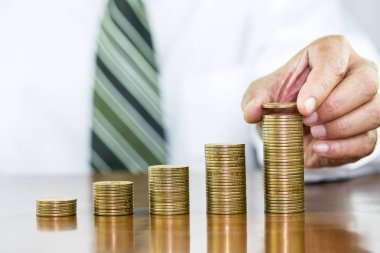 Madeni para Doları para sikke yığını üzerinde tutan işadamı el düzenlemek