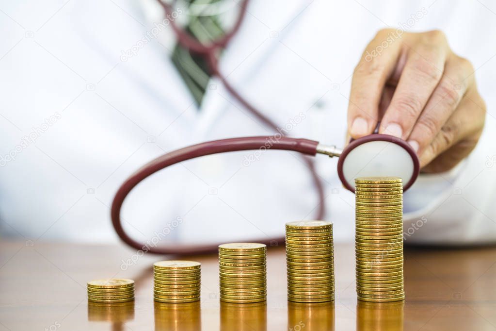 Doctor hand holding stethoscope checking stack of money coins ar