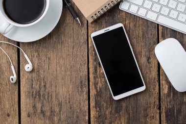 ahşap masa üstü görünümünde akıllı telefon ve bilgisayar.