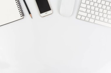 Akıllı telefon, bilgisayar ve ofis malzemeleriyle çalışan masa beyazının üst görünümü
