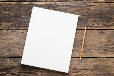Ahşap zemin üzerinde kalem olan boş beyaz tuval çerçeve.