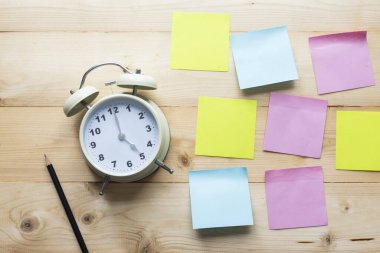 Üst görünüm alarm saati ve tahta arkaplanda yapışkan notlar.