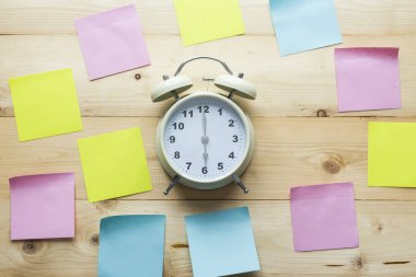 Üst görünüm alarm saati ve tahta arkaplanda yapışkan notlar.