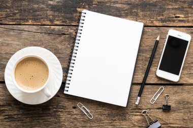 Boş defter ve kahve ahşap masada.