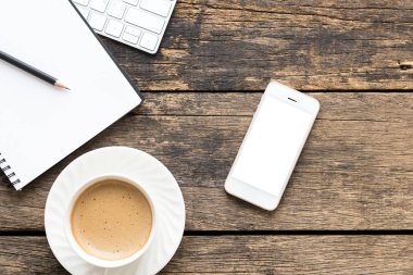 Kahve fincanı ve bilgisayar ile ahşap masa manzaralı akıllı telefonu kapat..