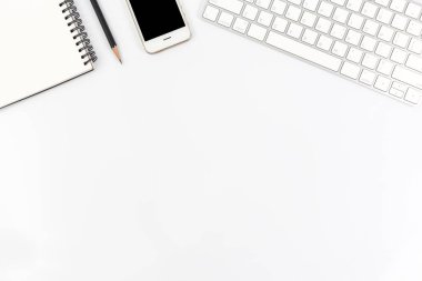 Akıllı telefon, bilgisayar ve ofis malzemeleriyle çalışan masa beyazının üst görünümü