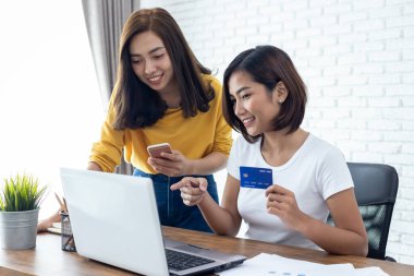 İnternetten alışveriş kavramı. Elinde kredi kartı ve cep telefonu olan iki genç kadın.