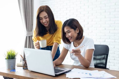 Two young asian woman working  laptop computer on wood desk in Home office