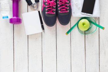 Sağlıklı spor konsepti, spor ayakkabıları, elma, su ve ahşap arka planda akıllı telefon, üst manzara