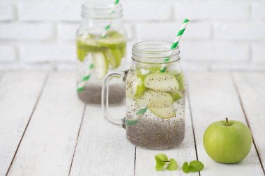 Elma yeşili dilimlenmiş cam içinde chia tohumları ve ahşap masada taze elmalar, sağlığa içelim.