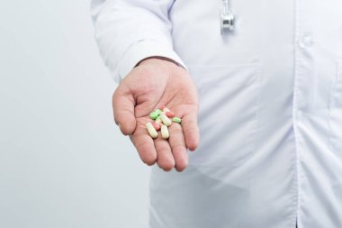 Beyaz arka planda hapları tutan doktor elini kapat.