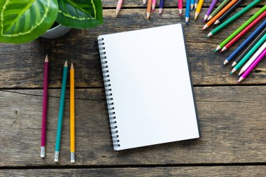 Boş defter ve eski ahşap masadaki kalemlerle üst kattaki ofis masasında.