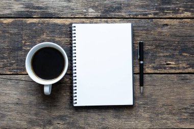 Tahta sehpanın üstünde kahve olan boş bir defter.