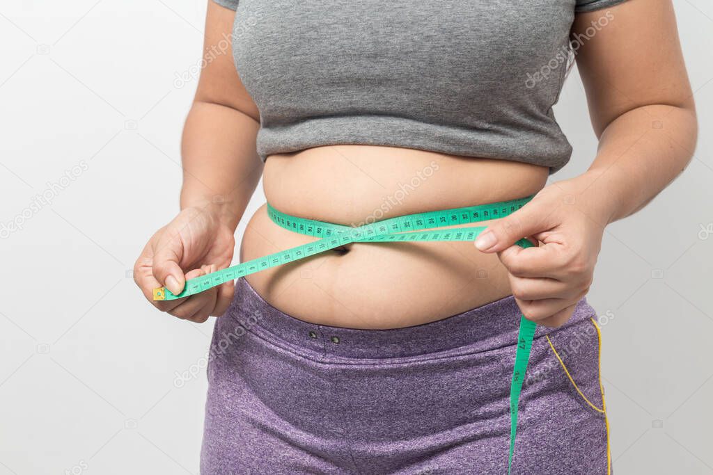 Overweight woman check out his body fat with green measuring tape for obesity on gray background, Healthy concept 