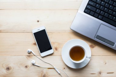 akıllı telefon çay fincanı ve bilgisayar ahşap masa manzaralı.