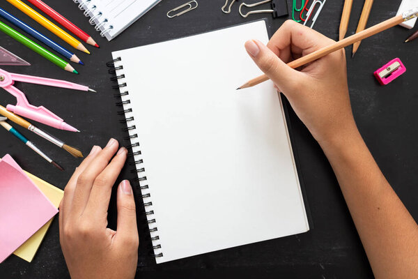 Ручной рисунок, чистая бумага с цветными карандашами и школьными принадлежностями на деревянном столе
