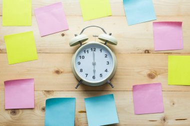 Üst görünüm alarm saati ve tahta arkaplanda yapışkan notlar.