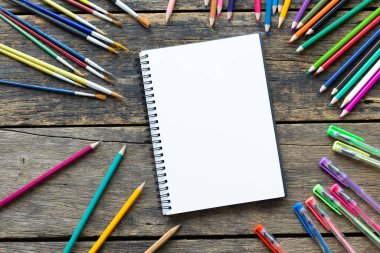 Boş defter ve eski ahşap masadaki kalemlerle üst kattaki ofis masasında.