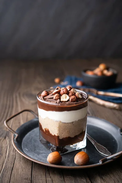 Layered dessert with chocolate mousse, cream cheese and whipped cream mixed with chestnut puree, topped with hazelnuts in a glass jar — Stock Photo, Image