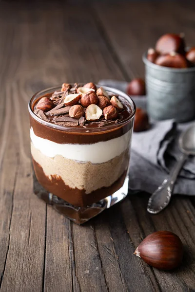 Layered dessert with chocolate mousse, cream cheese and whipped cream mixed with chestnut puree, topped with hazelnuts in a glass jar — Stock Photo, Image