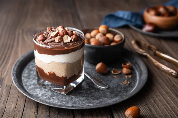 Layered dessert with chocolate mousse, cream cheese and whipped cream mixed with chestnut puree, topped with hazelnuts in a glass jar — Stock Photo, Image