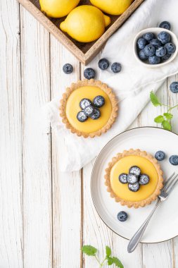 Limon kaymaklı ceviz kabuklu tart, üzerine taze yaban mersini serpiştirilmiş ve pudra şekerli.