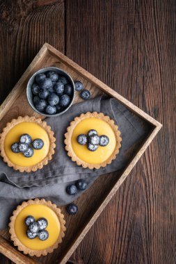 Limon kaymaklı ceviz kabuklu tart, üzerine taze yaban mersini serpiştirilmiş ve pudra şekerli.