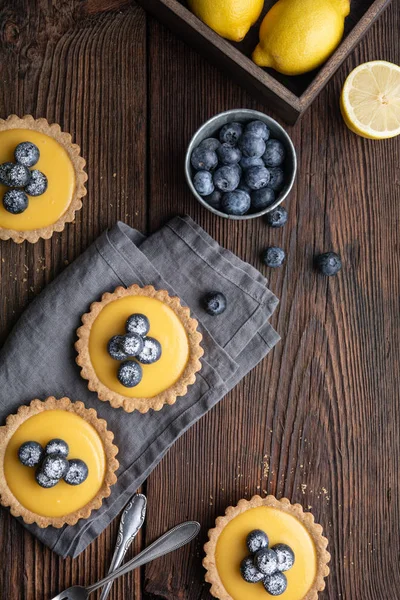 Tartelette à la croûte de noix avec garniture au citron, garnie de bleuets frais et saupoudrée de sucre en poudre — Photo