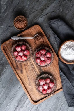Krem şanti ve ahududu püresinden yapılmış koyu çikolatalı kremayla dolu kakao kabuklu tartlar, üstüne de taze böğürtlen.