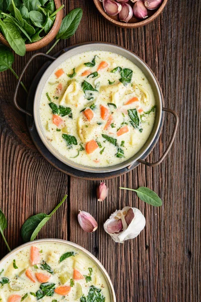 Сливочный суп из тортеллини со шпинатом, сельдереем, морковью и куриным бульоном — стоковое фото