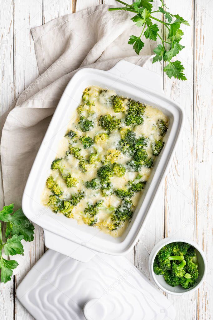 Simple broccoli and cheese casserole on white wooden background