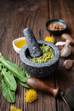 Sağlıklı karahindiba sosu badem, sarımsak, zeytin yağı ve parmesan peyniri ile taşralı ahşap zemin üzerine harç.