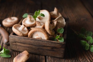 Kırsal ahşap arka planda bir kasede taze Shiitake mantarlarını destekleyen bir yığın bağışıklık.