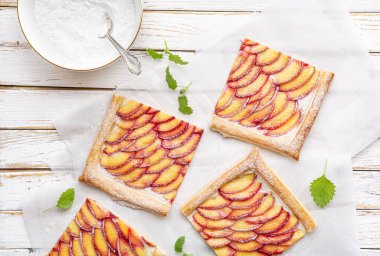 Lezzetli tatlı, sulu nektarinli börek krem peynirli tartlar ve kırsal ahşap arka planda pudra şekeri serpiştirilmiş.