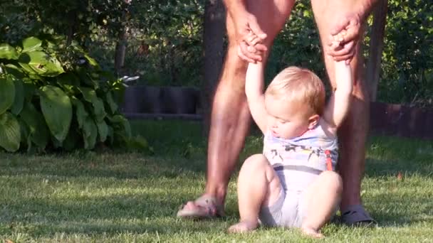 Menino aprendendo a andar na grama no quintal — Vídeo de Stock