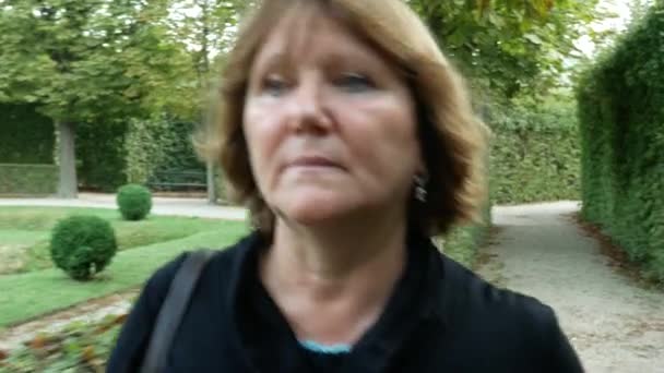 Retrato de mulher loira caminhando por um jardim bem cuidado Videoclipe