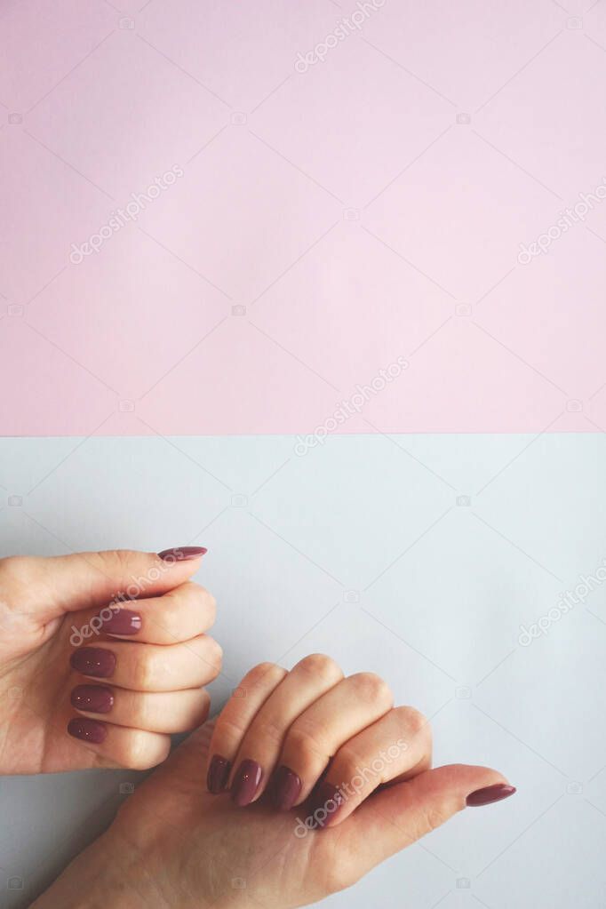 Violet manicure on blue and pink background.